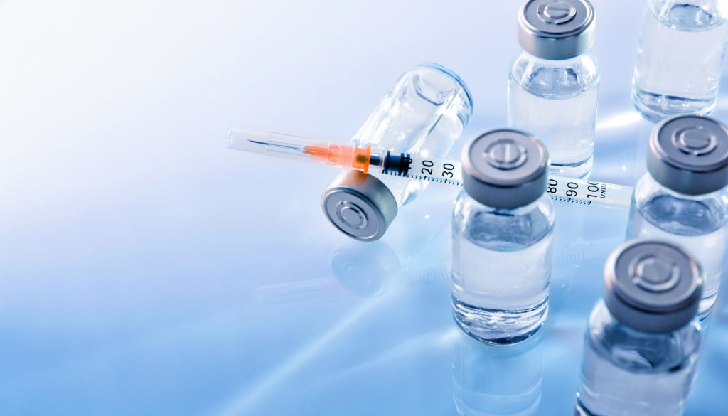 Vials with medication and syringe on a blue table