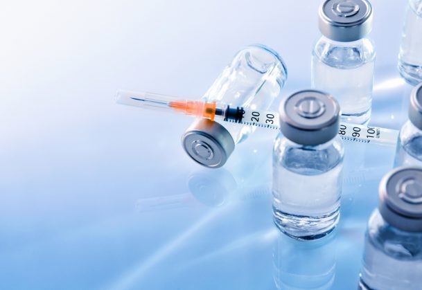 Vials with medication and syringe on a blue table