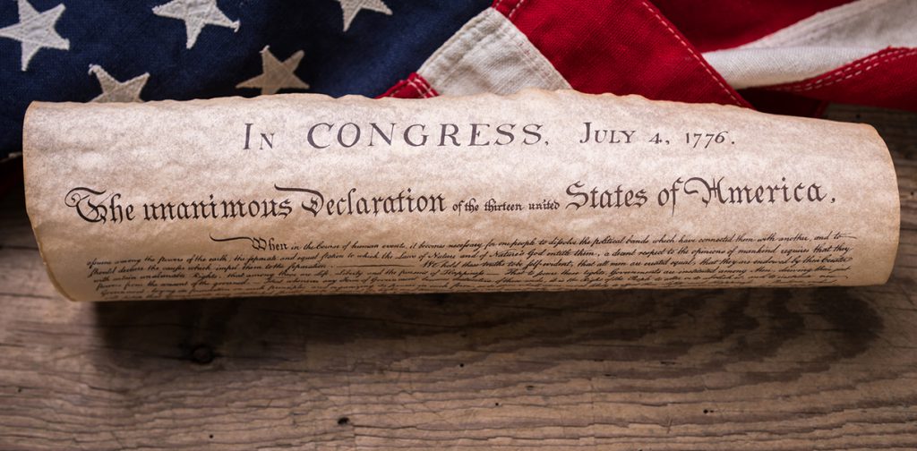 United States Declaration of Independence rolled in a scroll on a vintage American flag and rustic wooden board