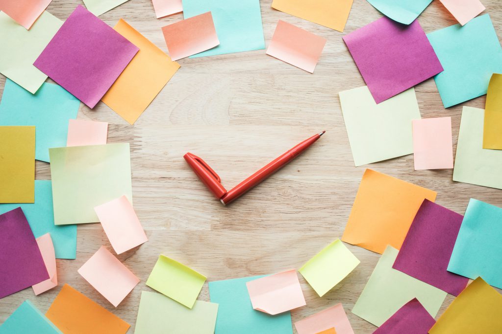 Sticky notes in a clock-like circle with pens as the clock hands