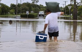 A man leaving his home walking through flood waters.