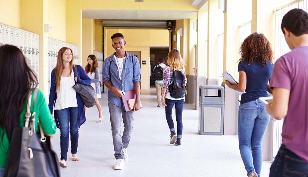 Group Of High School Students Walking Along Hallway