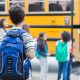 Child waiting as classmates board schoolbus