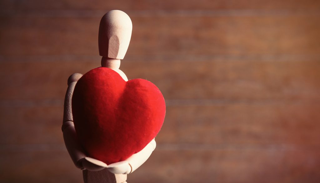 Wooden figure holding a red heart