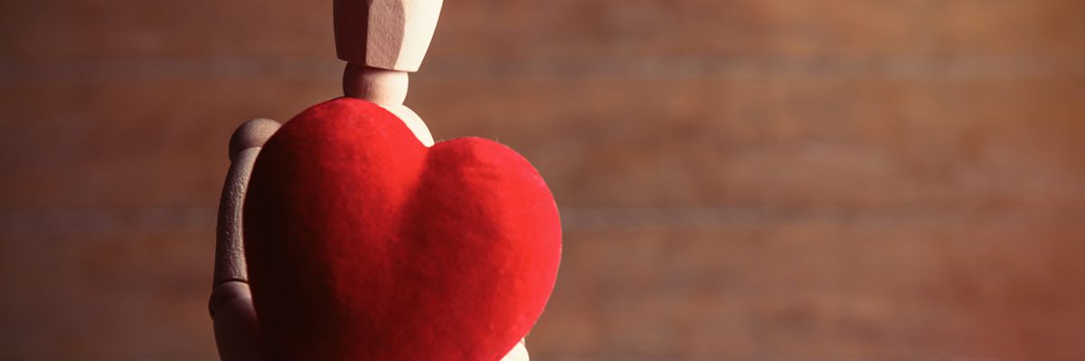 Wooden figure holding a red heart