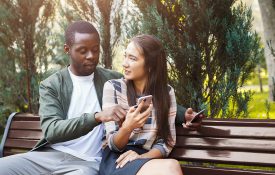 Couple looking at a phone sitting on a park bench