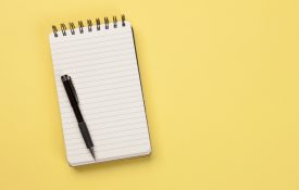 Blank lined notepad with a pen on a yellow surface