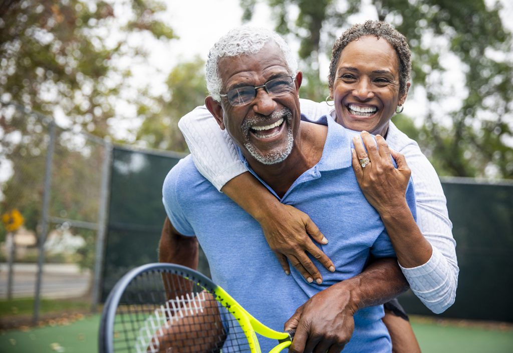 A senior couple together on the tennis court.