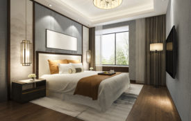 Photo of a hotel room with a large bed and window in the background.