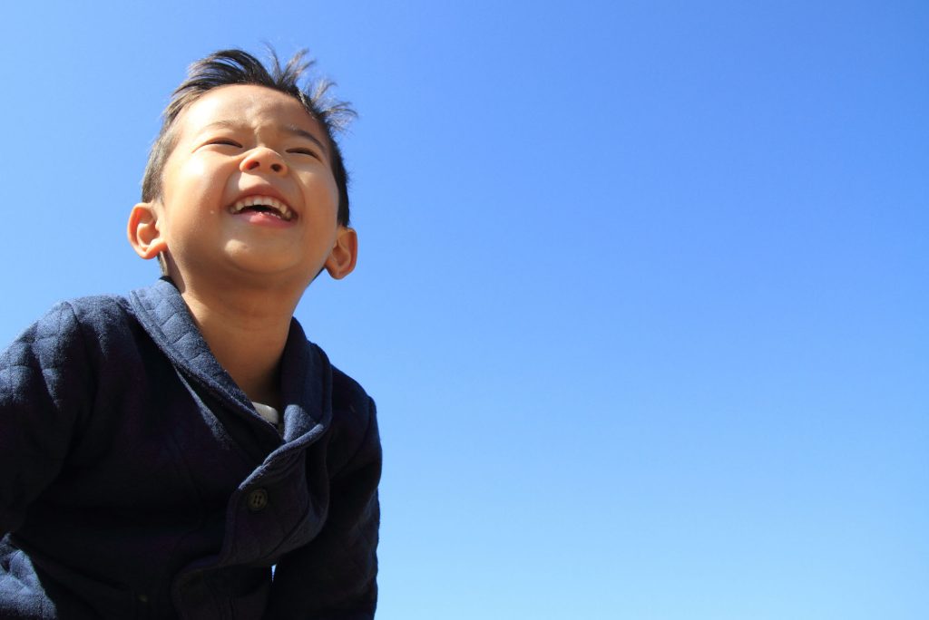 Happy little boy with the sky behind him.