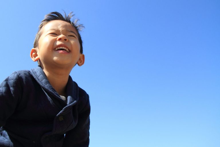 Happy little boy with the sky behind him.