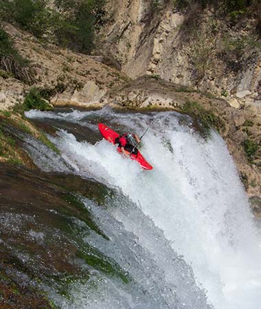 Photo of David Cole kayaking over white rapids.