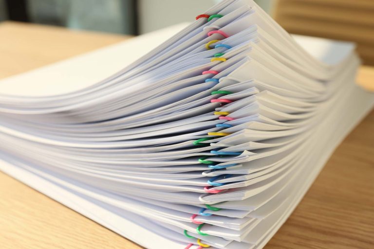 Closeup photo of a stack of documents with colorful paperclips separating each set.