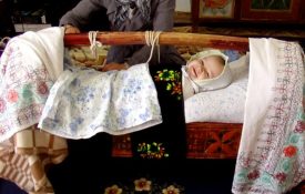 Tajik baby in gahvora and smiling at the camera.