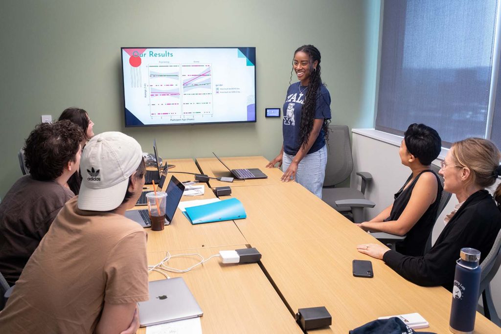 Lab members looking at a presentation being given in a small conference room.