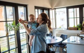A mother dances with her baby at home.