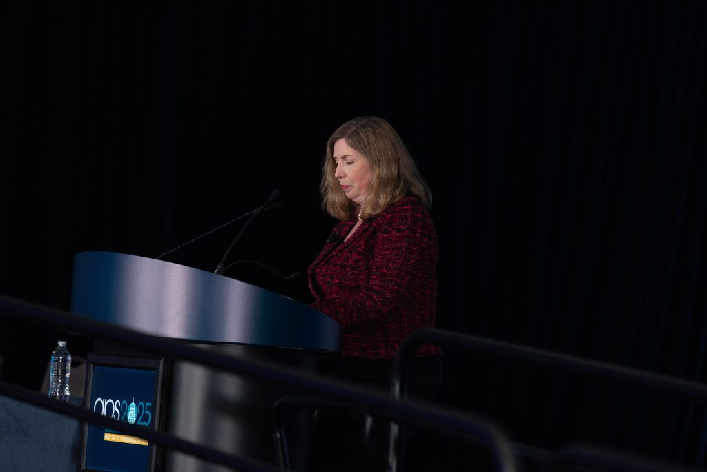 Angela Gutchess looks at her notes while speaking at a podium during the Collective Cognition session.