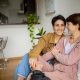 A lesbian couple sits on the couch together. They look and dress similarly.