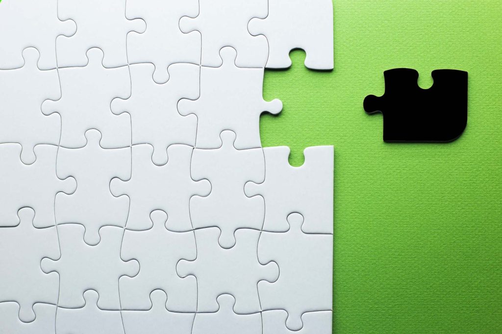 White puzzle with one piece missing to complete, but the missing piece is black and not the right shape.