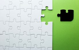 White puzzle with one piece missing to complete, but the missing piece is black and not the right shape.