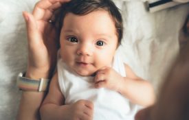 An infant in a white onesie.