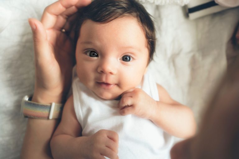 An infant in a white onesie.