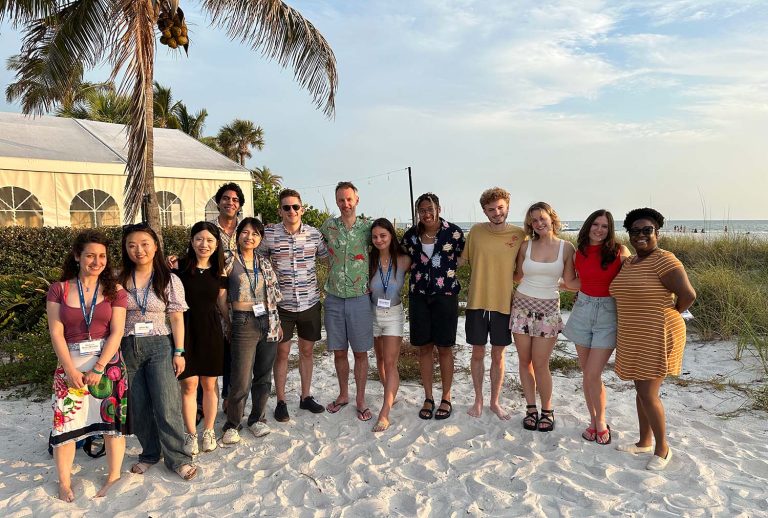 Firestone and his lab pose for a photo on a beach with a palm tree behind them.