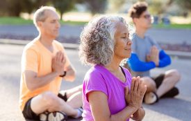 Senior woman meditating while during outdoor group fitness and yoga class