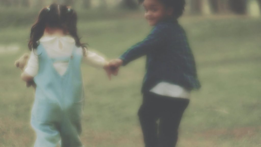 Blurry video of two children running away from the camera while holding hands.