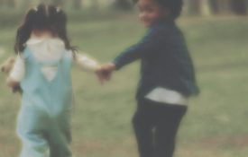 Blurry video of two children running away from the camera while holding hands.
