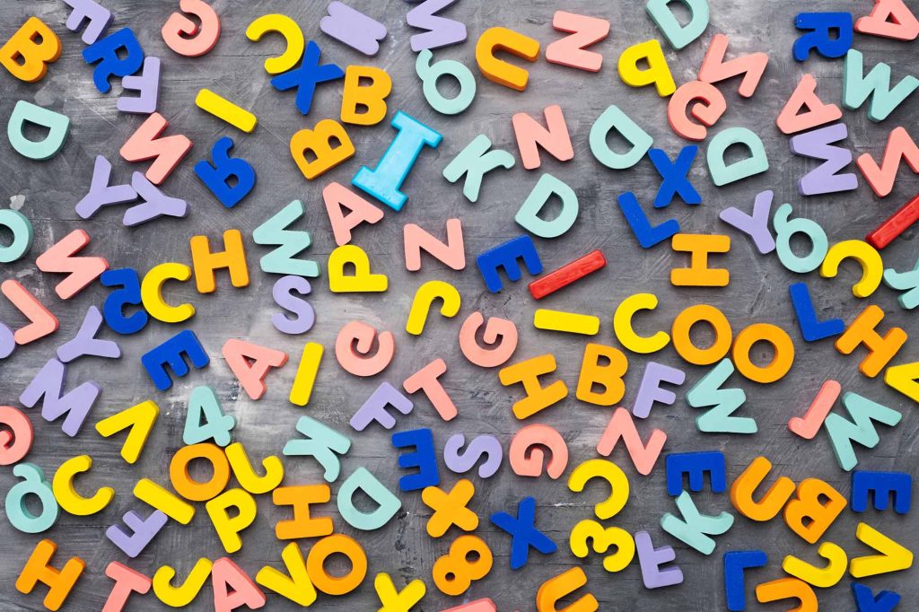 Colorful alphabet letters on gray background and texture.