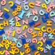 Colorful alphabet letters on gray background and texture.