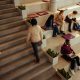 Students studying and walking on stairs in a bright, modern university hall, engaging in collaborative learning.