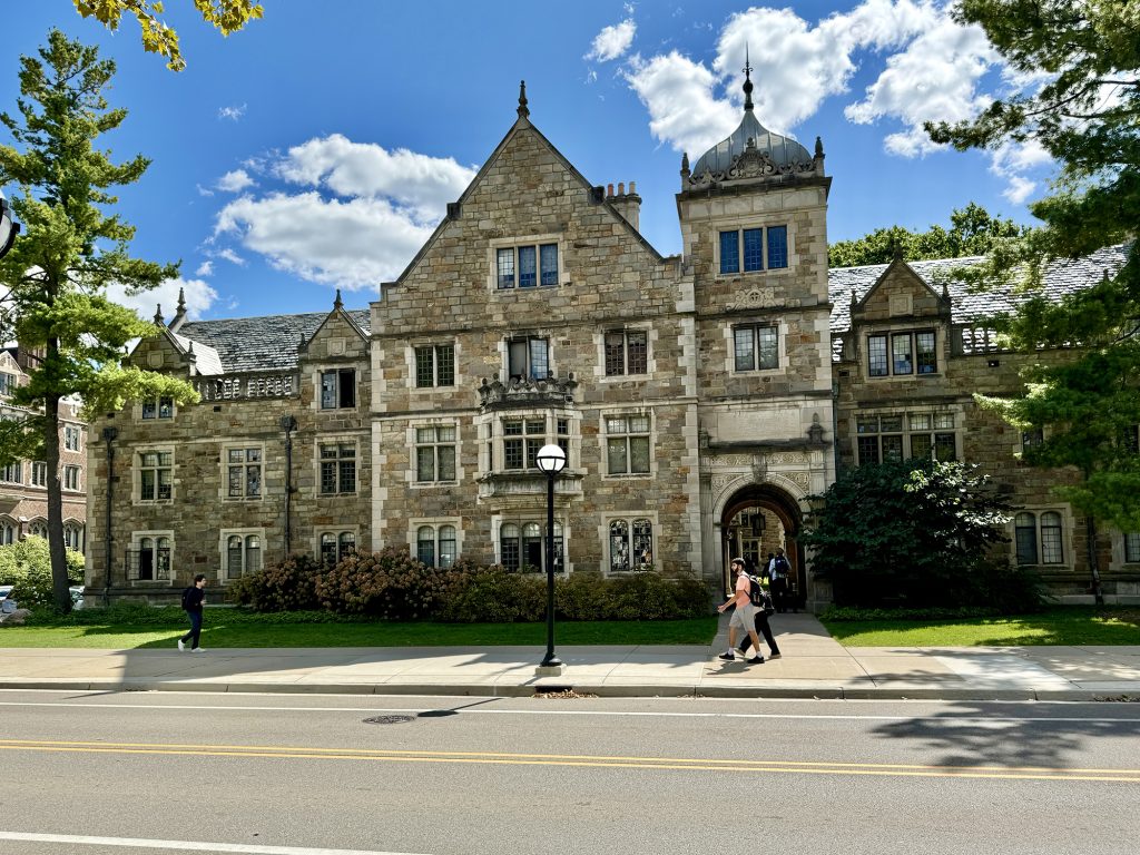 People walking in front of a large building on the University of Michigan campus