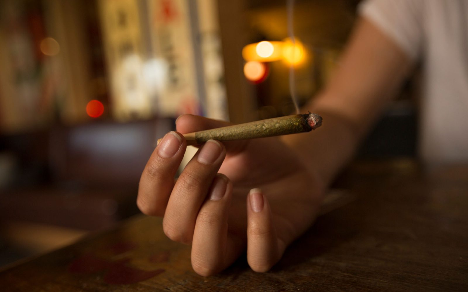 Person holding a cannabis joint that is lit.