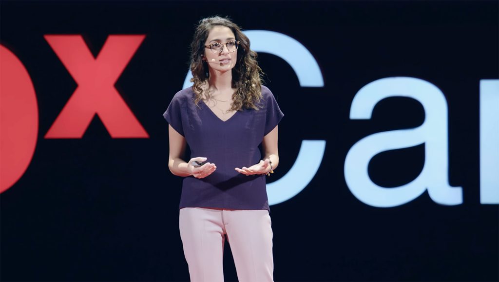 Dorsa Amir stands on the TEDx stage while giving her presentation.