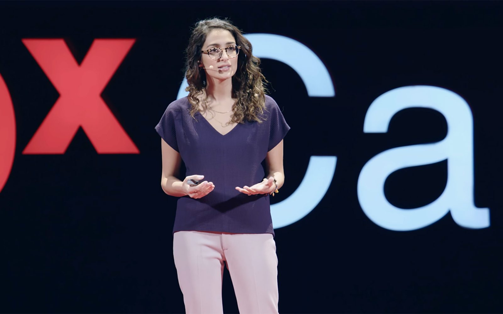 Dorsa Amir stands on the TEDx stage while giving her presentation.