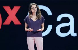 Dorsa Amir stands on the TEDx stage while giving her presentation.