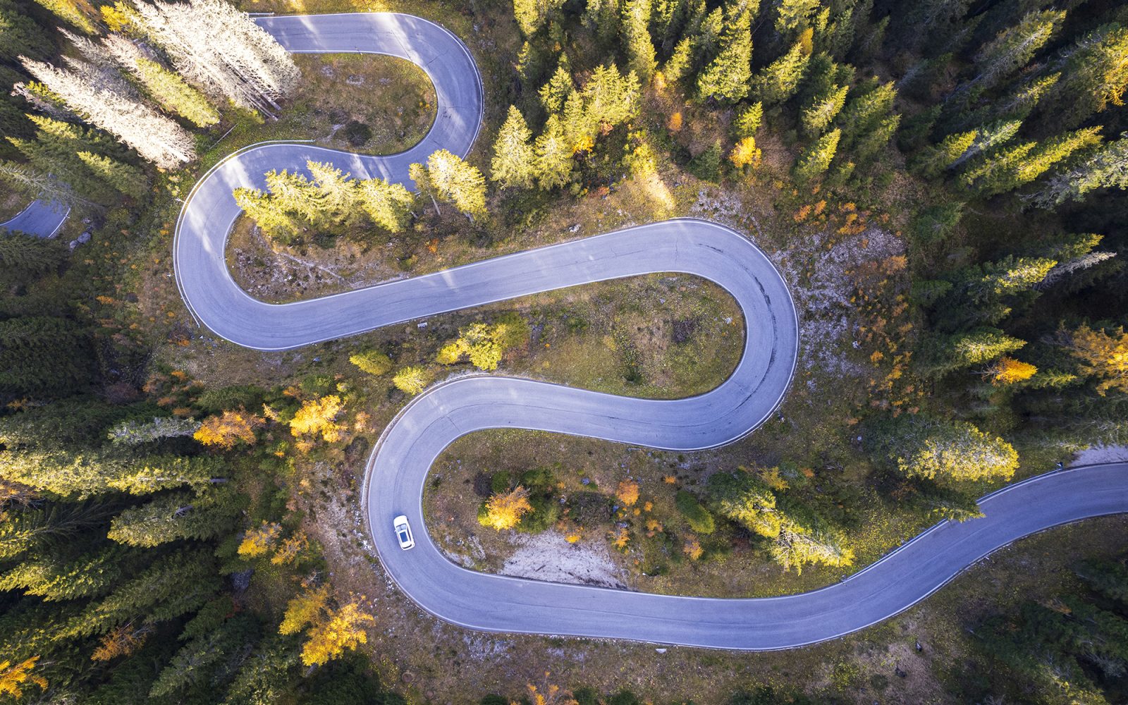 Car on empty serpentine road, Dolomites.