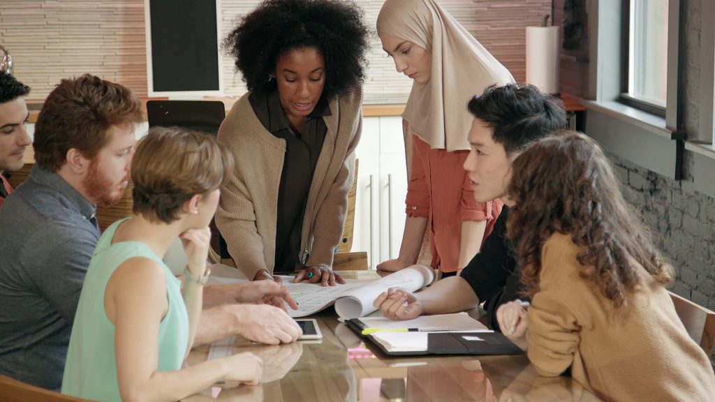 Close up of a young Black woman leading a diverse team meeting.