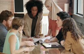 Close up of a young Black woman leading a diverse team meeting.