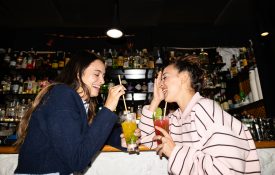 Young friends laughing enjoying drinks at bar