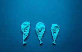 Three deflated blue balloons frowning on blue background.