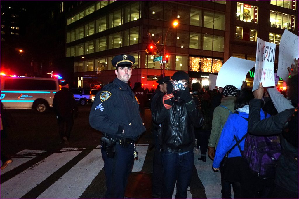 A police officer stands next to a photographer during a protest after Eric Garner's death.