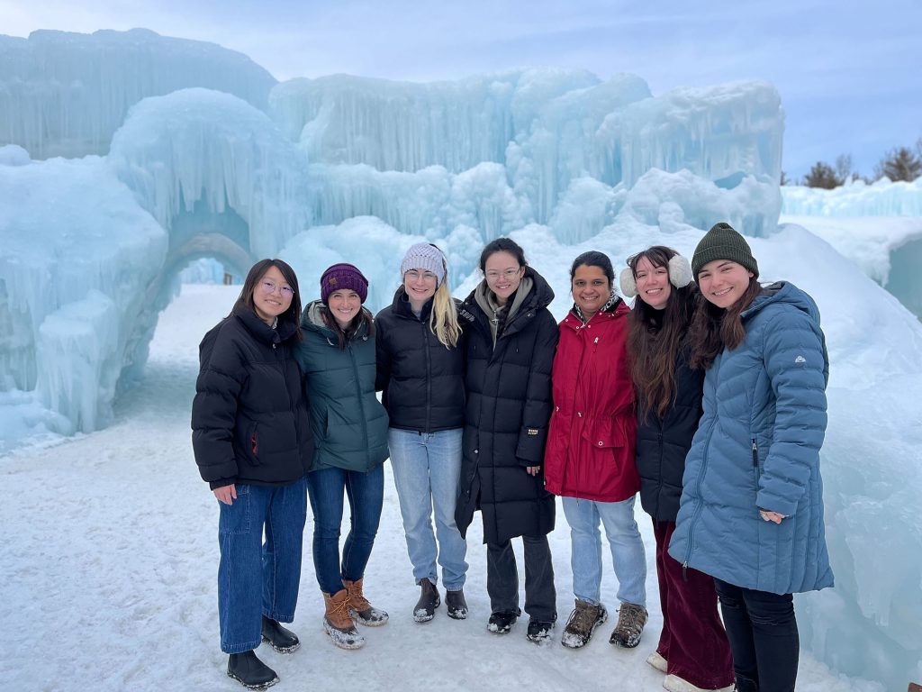 Emily Finn and her lab stand in front of large ice formations.