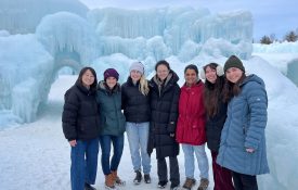 Emily Finn and her lab stand in front of large ice formations.