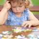 Toddler girl, solving puzzle on a table.
