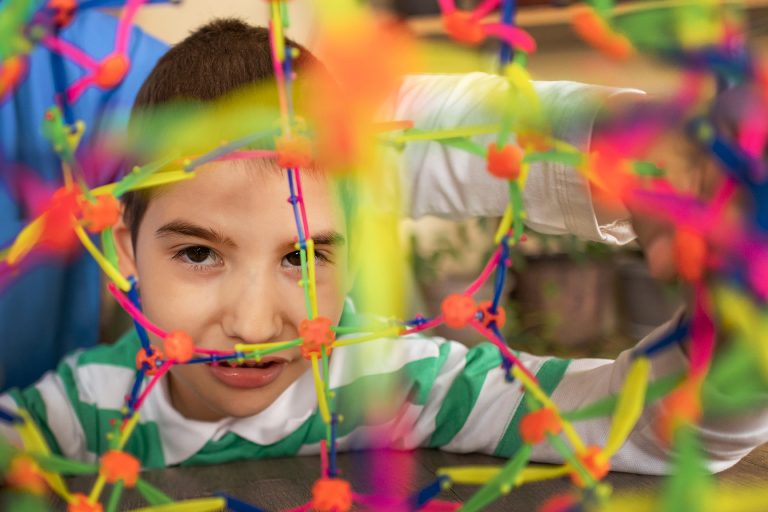 A female nurse works with an autistic boy using colorful sensory toys to develop motor skills.