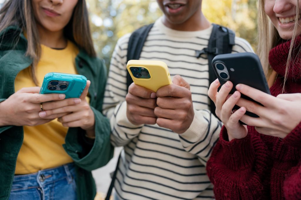 Close-up of three students looking at their phones.