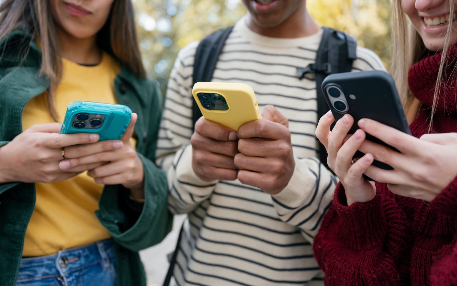 Close-up of three students looking at their phones.